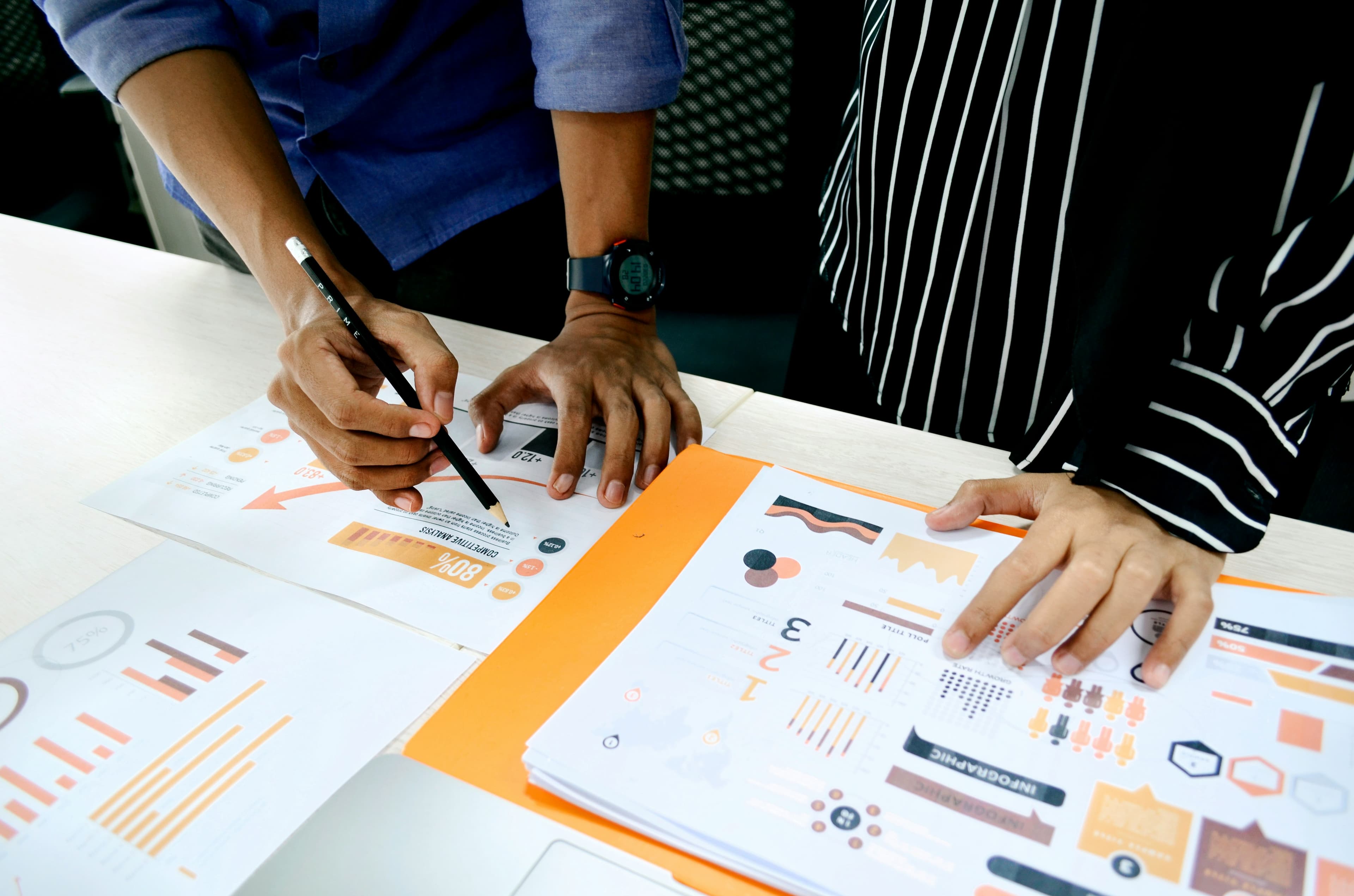 People reviewing printed charts and research material at a table.