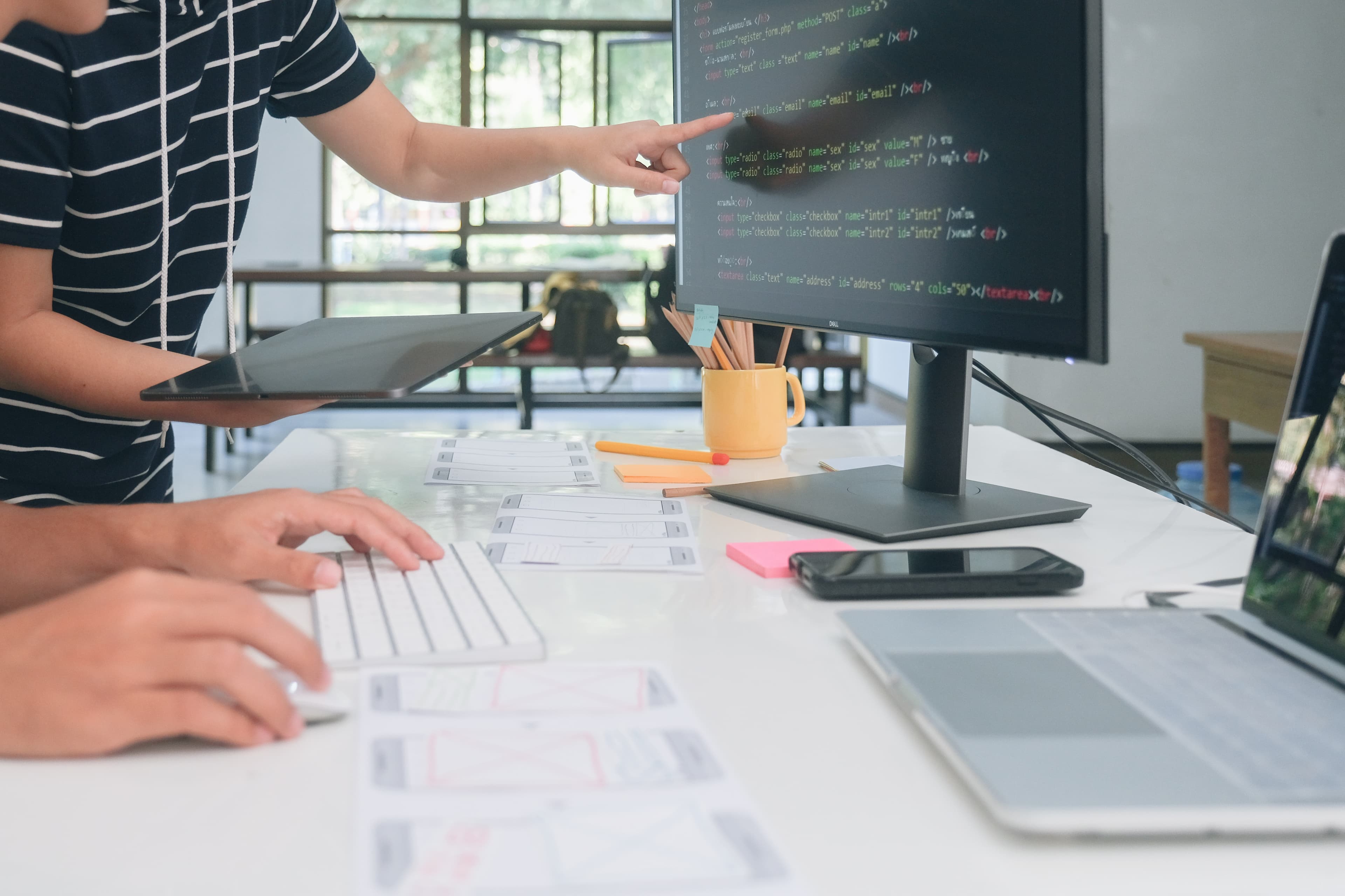 People reviewing software code and interface layouts at a workstation.